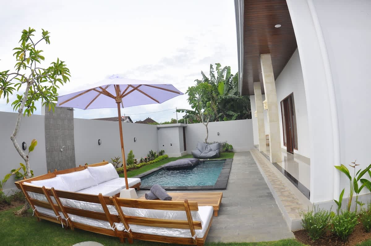 Exquisite outdoor seating crafted from premium teak wood, complemented by a stylish umbrella and cozy bean bags. Thoughtfully arranged by the pool, this setup creates the perfect blend of comfort and elegance for a serene oasis experience.